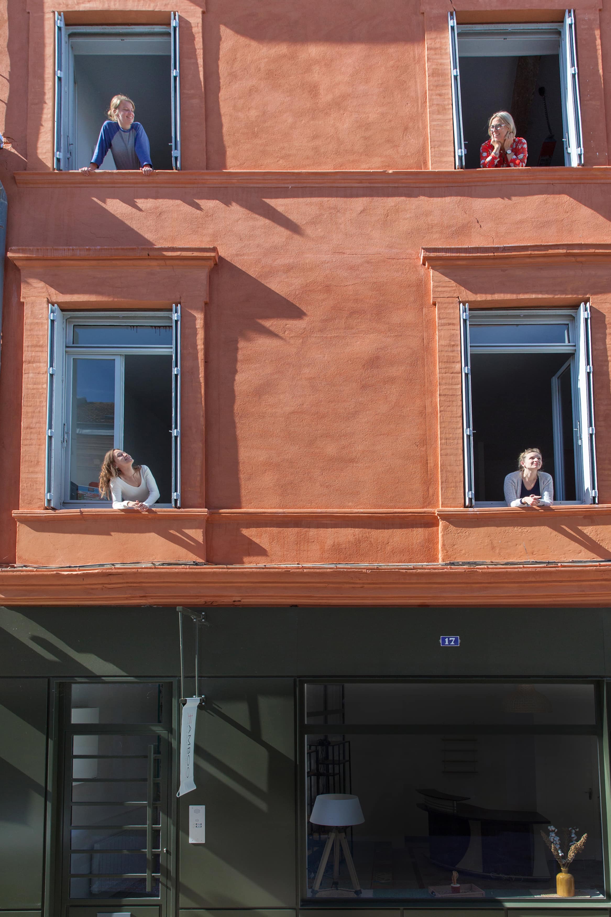 Les architectes de Bamboo Architectures aux fenêtres de la façade rose de l'agence