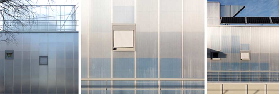 Façade en polycarbonate translucide du pôle petite enfance, aux reflets changeants et petites fenêtres carrées, surmontée de panneaux solaires